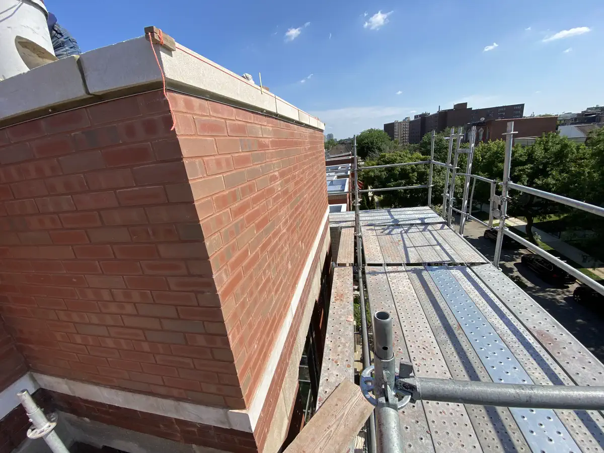 Rebuilt Chicago brick parapet wall with scaffolding after structural masonry repair